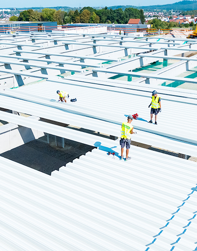Modernes Dachsystem von Strasser in Nürtingen von oben. Bauarbeiter arbeiten auf dem Dach